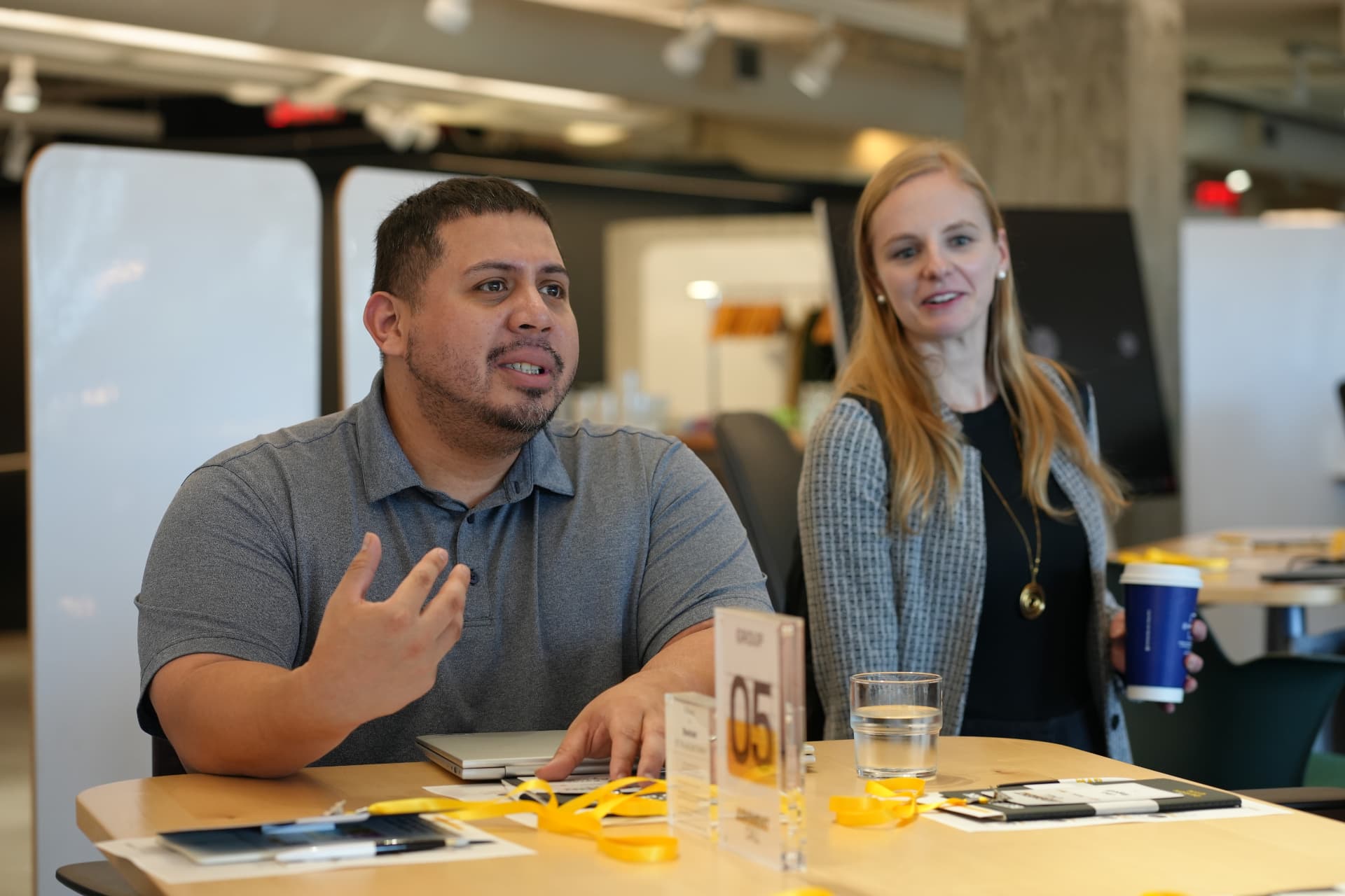 A leader shares his thinking at the table while a peer listens from behind