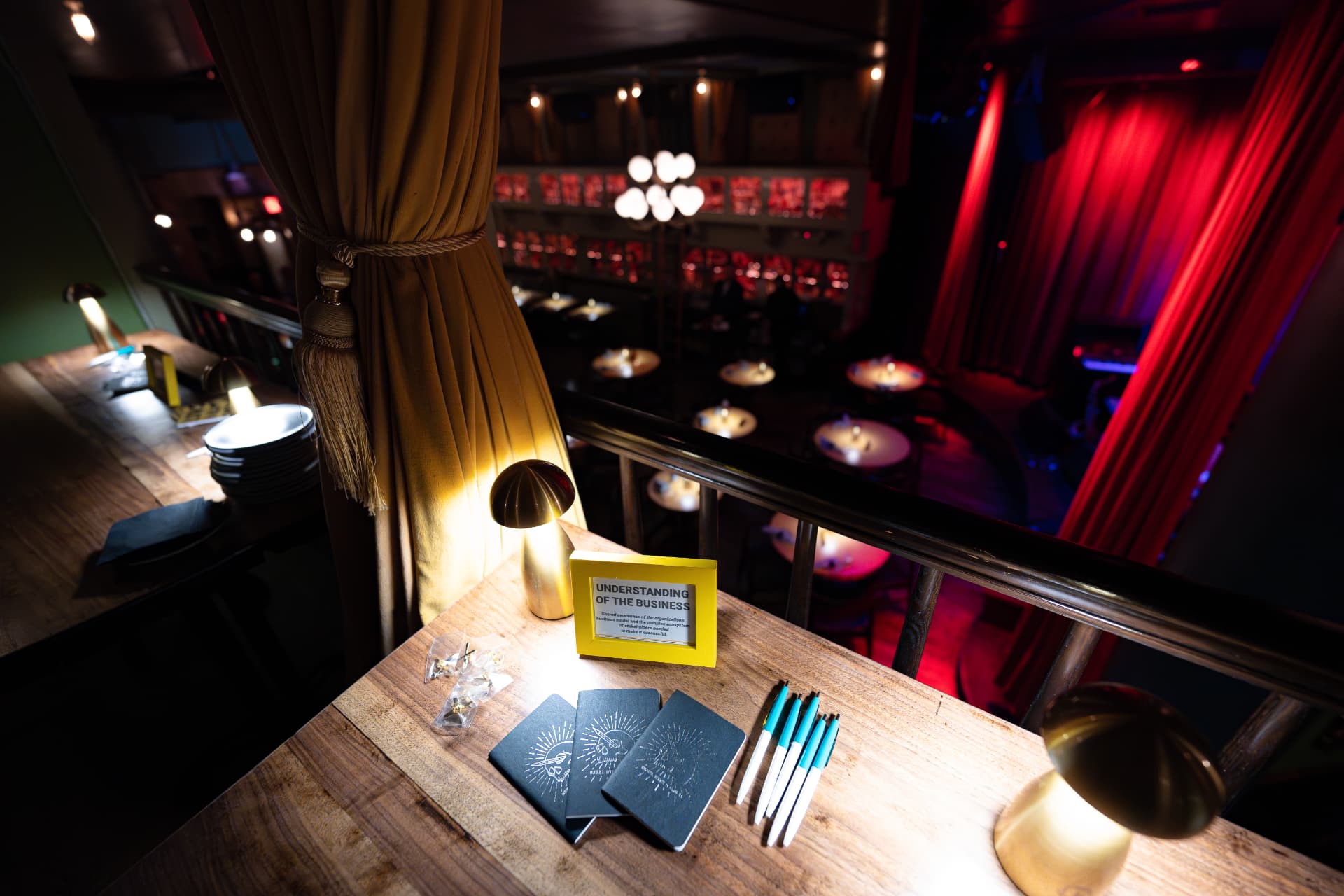 Notebooks, pens, and a framed prompt card laid out on a table overlooking the venue